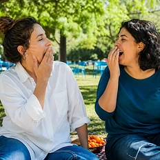 Duas amigas bocejam quase ao mesmo tempo durante um piquenique.