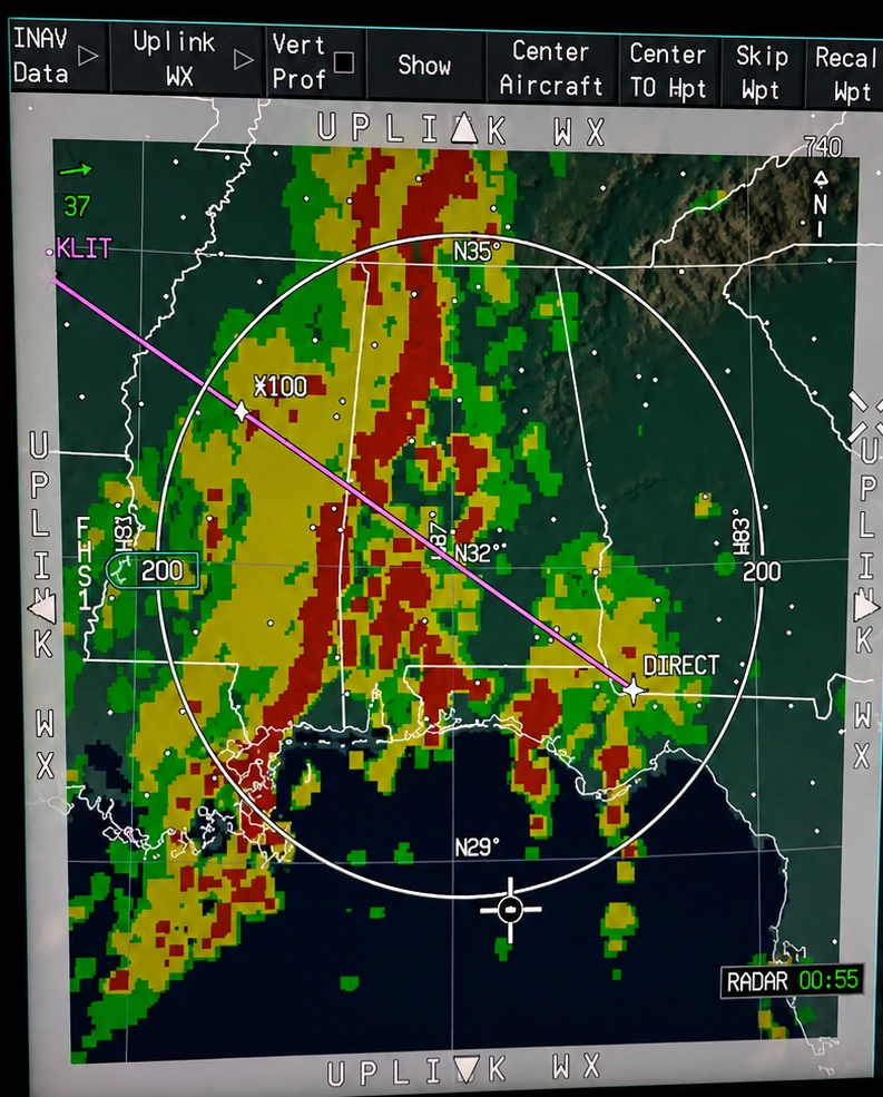 Tela do radar meteorológico de bordo, alcance de 200 milhas náuticas, com uma linha de instabilidade em verde, amarelo e vermelho atravessando a frente do avião e a rota em magenta contornando os núcleos.